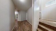 Located in North Las Vegas, NV, this two-story home offers three bedrooms, three bathrooms, and a well-organized layout across two floors. The main level features an open-concept kitchen and living area with warm-toned wood-look tile flooring, honey-oak cabinetry, a breakfast bar with decorative corbels, and recessed lighting. The living room is carpeted and spacious, illuminated by a pendant light. A hallway with durable wood-look flooring connects the main living spaces, with carpeted stairs leading to the upper level. The ground floor also includes an attached garage with a concrete floor and automatic opener, as well as a dedicated laundry room equipped with a full-size washer and dryer and built-in shelving. Upstairs, the three bedrooms feature plush carpeting and natural light from windows. The generously sized primary bedroom includes a walk-in closet with wrap-around wire shelving. The bathrooms are cleanly appointed with wood-look flooring, single-sink vanities with wood cabinetry, and tub-shower combinations. Two closets provide ample storage throughout. The home's neutral color palette and textured ceilings create a clean, move-in ready atmosphere throughout.