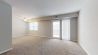 This single-floor residence offers a well-organized layout designed for comfortable everyday living. The living room serves as the heart of the unit, featuring soft wall-to-wall carpeting, neutral gray walls, and a ceiling fan overhead. A sliding glass door fitted with vertical blinds opens directly onto a private balcony, while an adjacent window allows additional natural light to fill the space.

The galley-style kitchen is outfitted with white cabinetry, granite-look countertops, and stainless steel appliances, including an electric range, built-in microwave, and dishwasher. Light wood-look flooring and a clean, bright aesthetic give the kitchen a modern feel. A dedicated laundry area houses a full-sized washer and dryer with overhead shelving for added storage convenience.

The two bedrooms are generously sized, each finished with plush carpeting, soft gray walls, and individual windows with blinds that provide natural light and privacy. One bedroom includes a bifold-door closet with ample storage space.

The bathroom features a full tub and shower combination with built-in shelving, complemented by wood-look flooring and clean white fixtures. Overall, the unit presents a cohesive, move-in-ready environment with practical amenities throughout.