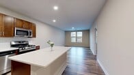 This contemporary 880 square foot apartment offers a thoughtfully designed living space on a single floor. The heart of the home is an open-concept kitchen and living area, featuring a gourmet kitchen with rich wood cabinetry, stainless steel appliances, and a generous island with a white quartz countertop. The kitchen's subway tile backsplash adds a touch of classic elegance.

The spacious bedroom, measuring 150 square feet, is bathed in natural light from large windows and features a modern ceiling fan. The full bathroom boasts a single vanity with ample counter space, a large mirror, and a combination tub/shower.

Throughout the apartment, you'll find high-quality vinyl plank flooring that mimics the warmth and texture of hardwood. The neutral color palette of the walls creates a bright, airy atmosphere. A walk-in closet provides generous storage space with wire shelving systems.

Large windows in the living areas and bedroom not only flood the space with natural light but also offer views of the surrounding area. The apartment's layout is efficient and functional, making the most of its 880 square feet to create a comfortable and stylish living environment.