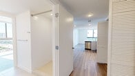 Located in Miami, FL, this modern 2-bedroom, 2-bathroom residence offers a clean, contemporary design throughout its thoughtfully laid-out single floor. Wide-plank wood-style flooring flows seamlessly through the living areas and bedrooms, complementing the crisp white walls and recessed lighting that create a bright, airy ambiance.

The open-concept kitchen is well-appointed with stainless steel appliances — including a French door refrigerator, electric range, built-in microwave, and dishwasher — paired with white cabinetry and light quartz countertops. The adjacent living area benefits from an abundance of natural light and connects easily to the rest of the home.

The primary bedroom is generously sized, featuring floor-to-ceiling corner windows that frame sweeping panoramic views of the Miami skyline and cityscape, flooding the room with sunlight. A spacious walk-in closet with wire shelving provides ample storage. The second bedroom also offers a closet with sliding doors and its own access to a full bathroom.

Both bathrooms are finished with light tile flooring, white vanities, and clean, minimalist fixtures. A dedicated laundry room houses a full-size top-load washer and dryer. A hallway with additional closet storage completes the functional layout of this bright, move-in ready Miami residence.