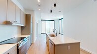 Located in the heart of Midtown Atlanta, this contemporary two-bedroom, two-bathroom residence offers a thoughtfully designed open-concept layout finished with light hardwood flooring throughout. The combined kitchen and living area serves as the centerpiece of the home, anchored by a large kitchen island with a white quartz countertop, an undermount sink with a matte black faucet, and warm taupe cabinetry. Stainless steel appliances, including a refrigerator, dishwasher, and range, complete the kitchen. Pendant and recessed lighting add a modern touch to the space. Dramatic floor-to-ceiling windows frame sweeping panoramic views of Atlanta's lush tree canopy and cityscape, flooding the living area with abundant natural light. Both bedrooms continue the light, airy aesthetic with the same hardwood flooring and large windows offering elevated city views. Each bedroom is served by a well-appointed closet featuring built-in shelving and hanging systems. The primary bathroom offers a dual-sink vanity with wood-toned cabinetry, white quartz countertops, matte black fixtures, and marble-style tile flooring, along with direct access to a walk-in closet. The second bathroom features a clean, minimalist design with a single vanity, tub-shower combo, and coordinating finishes. A connecting hallway ties all spaces together seamlessly.