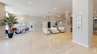 Located at 23 Rock Hill Rd in Bala Cynwyd, PA, this single-floor communal space offers a thoughtfully designed, open-plan layout that seamlessly blends functionality with contemporary style. The polished concrete flooring extends throughout, lending a clean, cohesive aesthetic to the entire floor.

The main living and lounge area is bathed in natural light, courtesy of expansive floor-to-ceiling windows and glass double-entry doors that frame views of the surrounding neighborhood. Oversized woven pendant light fixtures hang above a seating arrangement featuring rich cognac leather sofas and a round coffee table, creating a warm and welcoming entrance lounge. Lush indoor trees and potted plants add a vibrant, organic element throughout the space.

Deeper into the floor, a secondary lounge area features crisp white upholstered seating beneath a striking linear pendant chandelier with adjustable directional spotlights. Vertical wood slat accent walls and black steel-framed glass partitions define zones without interrupting the open flow. A high-top communal table with bar-height seating sits adjacent to a glass-enclosed conference room, making the space well-suited for both casual gatherings and focused work sessions. A large-screen television and built-in shelving complete the amenity-rich environment, while a dedicated elevator provides convenient access to the rest of the building.