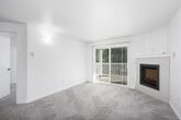 This single-floor residence offers a well-organized layout with a bright, neutral aesthetic throughout. The living area serves as the centerpiece of the space, featuring plush wall-to-wall carpeting and a framed fireplace with a classic white mantel. Vertical blinds frame a sliding glass door that opens onto a private outdoor balcony, allowing natural light to fill the room and providing views of surrounding greenery.

The entryway transitions seamlessly from wood-look flooring into the carpeted living space, offering a practical and visually defined threshold. The kitchen is thoughtfully designed with two-tone cabinetry — white upper cabinets paired with sage-green lower cabinets — complemented by white countertops and wood-look flooring. Stainless steel appliances, including a refrigerator, dishwasher, and range, add a modern touch, while recessed lighting keeps the space well-lit.

The bedroom is a comfortable, carpeted room with a window offering natural light and outdoor views. The bathroom is clean and updated, featuring a wide vanity with white cabinetry, a large mirror, brushed gold fixtures, and a full tub-shower combination. Wood-look tile flooring ties the bathroom's finishes together cohesively. The overall ambiance is light, clean, and move-in ready.