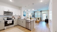 Located in Wesley Chapel, FL, this thoughtfully designed 3-bedroom, 3-bathroom home offers a bright, modern living experience on a single floor. The open-concept kitchen and living area serves as the heart of the home, showcasing white shaker cabinetry, granite countertops, a subway tile backsplash, stainless steel appliances, and a peninsula island with seating — perfect for casual dining and entertaining. Pendant lighting and light wood-style flooring tie the space together seamlessly as it flows into the living room, which features a ceiling fan, large windows, and a private exterior door that fills the area with natural light. The primary bedroom offers a comfortable retreat with plush carpeting, a ceiling fan, and a dedicated en-suite bathroom featuring a glass-enclosed shower and light wood-style flooring. Additional bedrooms are well-sized with carpet, ceiling fans, and ample natural light from large windows. The bathrooms maintain a clean, contemporary aesthetic with granite-topped vanities and neutral finishes. Two closets provide practical storage throughout. The overall ambiance is bright and airy, with a cohesive neutral palette that enhances the sense of openness across the entire home.