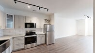 Located at 8700 Seeing Trail Rd in Wake Forest, NC, this well-appointed one-bedroom, one-bathroom residence offers a thoughtfully designed layout across a single floor. The open-concept kitchen, dining, and living area creates a seamless flow throughout the main living space. The kitchen is a standout feature, showcasing gray shaker-style cabinetry, granite countertops, a subway tile backsplash, a stainless steel farmhouse sink, and a full suite of stainless steel appliances including a range, microwave, dishwasher, and refrigerator. A built-in wine rack adds a charming detail, while black track lighting provides stylish, adjustable illumination. Hardwood-style flooring runs throughout the main living areas, complementing the bright, neutral color palette. The living and dining space is open and airy, with natural light filtering in through window treatments. The bedroom offers plush carpeting, a ceiling fan, and windows that invite natural light, with direct access to both a closet and the bathroom. The bathroom features a tiled shower-tub combination, granite-topped vanity, gray cabinetry, and a convenient open shelving unit. A dedicated laundry area completes this efficiently designed residence.