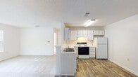 Located at 2162 Mill Stream Cir in Creedmoor, NC, this single-floor residence offers a functional and well-organized layout suited for comfortable everyday living. The kitchen serves as a central hub of the home, featuring ample white cabinetry extending to the upper walls, light countertops, a coil electric range with overhead ventilation, a dishwasher, a full-size refrigerator, and a double-basin sink set into a peninsula that opens toward the living area. Wood-style vinyl flooring runs throughout the kitchen and connecting hallways, adding warmth and durability underfoot. The living and dining areas transition into carpeted spaces that provide a softer feel, with natural light streaming in through sizable windows fitted with horizontal blinds. The bedrooms are carpeted and bright, with at least one room featuring a ceiling fan with integrated lighting. Each bedroom benefits from natural light through exterior-facing windows. The full bathroom is clean and efficiently designed, offering a single-sink vanity with white cabinetry, a mirrored medicine cabinet, wood-style flooring, and a full-size soaking tub with a shower combination. Textured ceilings are consistent throughout the home, and the neutral white walls provide a versatile canvas. The overall ambiance is clean, practical, and move-in ready.