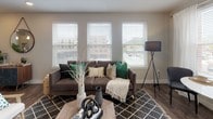 Located at 203 Perry St in Castle Rock, Colorado, this single-floor residence offers a thoughtfully designed open layout with contemporary finishes throughout. The living room is a bright, welcoming space anchored by a bank of large windows fitted with white horizontal blinds, allowing ample natural light while framing views of the surrounding urban streetscape. Rich, dark hardwood-style flooring flows consistently through the main living areas, adding warmth and cohesion to the design.

The kitchen is well-equipped with dark walnut-toned cabinetry, stainless steel appliances including a refrigerator, range, microwave, and dishwasher, and a white subway tile backsplash with under-cabinet lighting. A central island with a white countertop provides additional prep space and casual seating. Adjacent to the kitchen, a dining nook with window views offers an intimate setting for meals.

The bedrooms are carpeted and comfortably scaled, each featuring windows with blinds and curtains. The primary bathroom includes a wide vanity with dark cabinetry, a large mirror, wood-look tile flooring, and a soaking tub with subway tile surround. A dedicated laundry area accommodates a stacked washer and dryer unit alongside shelving and hanging storage, adding practical convenience to the residence.