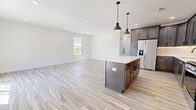This well-appointed 3-bedroom, 2-bathroom residence at 688 Pennsylvania Ave in Elizabeth, NJ offers a thoughtfully designed single-floor layout with modern finishes throughout. The open-concept kitchen and living area serves as the heart of the home, anchored by a large central island with a white quartz countertop and dark cabinetry, complemented by striking pendant lights overhead. Full-height cabinetry in a warm gray-brown tone, stainless steel appliances, and light wood-look flooring complete the kitchen's contemporary aesthetic. The expansive living area flows seamlessly from the kitchen, bathed in natural light from a large window. The generously sized primary bedroom features sliding glass doors that open to a private balcony, offering open views of the surrounding neighborhood. The two well-sized secondary bedrooms feature light wood-look flooring and windows that bring in natural light. Both bathrooms are elegantly finished with marble-look tile flooring and walls, dark-framed glass shower enclosures, white soaking tubs, and dark wood vanities with white quartz countertops and backlit mirrors. A dedicated closet provides ample built-in shelving and hanging storage. Hallways connect the rooms with ease, and recessed lighting throughout adds a polished, modern feel to the entire space.