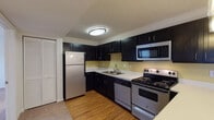 Located at 215 Codell Dr in Lexington, Kentucky, this single-floor unit offers a well-organized layout designed for comfortable everyday living. The kitchen is a standout feature, showcasing bold dark cabinetry that contrasts sharply with light countertops and warm hardwood-style flooring. Stainless steel appliances—including a refrigerator, electric range, built-in microwave, and dishwasher—provide a cohesive, modern aesthetic. A peninsula with pendant lighting separates the kitchen from the dining area, creating a natural transition between the two spaces.

The living area is bright and welcoming, finished with neutral carpet and anchored by a ceiling fan with integrated lighting. A set of glass-paned French doors opens to an outdoor space, allowing natural light to flow in and providing easy access to the exterior. Adjacent to the living area, the dining space benefits from additional pendant lighting, reinforcing the open-concept feel.

The bedrooms are carpeted and neutrally finished, each offering natural light through blinded windows. Generous closet space—including a walk-in closet—provides practical storage. The bathroom features tile flooring, a dark-cabineted vanity with a white countertop, and a full tub-shower combination with chrome fixtures, delivering a clean and functional design throughout.