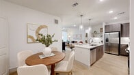 Located in Houston, TX (77085), this single-story, 3-bedroom, 2-bathroom home offers a thoughtfully designed layout with modern finishes throughout. Light wood-look flooring runs continuously across the space, creating a cohesive and airy aesthetic.

The open-concept kitchen and living area serves as the heart of the home. The kitchen is outfitted with flat-front, wood-toned cabinetry, white quartz countertops, stainless steel appliances including a side-by-side refrigerator with ice maker, electric range, and built-in microwave. Under-cabinet lighting adds a polished touch, while a kitchen island provides additional prep and seating space. A built-in desk area adjacent to the kitchen offers a functional workspace.

The primary bedroom is a well-proportioned retreat filled with natural light from large windows dressed with blinds and curtains, complemented by a ceiling fan. A walk-in closet with wire shelving provides generous storage.

Both bathrooms feature the same refined design language: wood-toned vanity cabinetry, white countertops, large-format tile surrounds in the tub/shower combos, and recessed overhead lighting. The dedicated laundry room houses a side-by-side washer and dryer with built-in shelving above.

The entryway is bright and welcoming, with a transom window above the front door allowing additional natural light into the space.