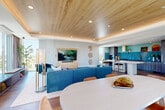 Located at 420 Mendocino Ave in Santa Rosa, CA, this thoughtfully designed space offers a seamless open-plan layout that connects the living, dining, and kitchen areas. The living area is anchored by a warm wood-paneled tray ceiling with recessed lighting, wide-plank hardwood floors, and expansive floor-to-ceiling windows that flood the space with abundant natural light and frame sweeping views of the surrounding cityscape. The kitchen is a true standout, featuring bold teal zellige tile extending from counter to ceiling, wood-grain cabinetry with brushed gold hardware, dark stone countertops, a gas cooktop beneath a striking gold range hood, and a sculptural white island with bar seating — a sophisticated blend of color and texture. The dining area accommodates a large oval table, positioned to take advantage of the open layout and natural light. A set of glass doors connects the interior to a spacious rooftop terrace, where an outdoor kitchen with a built-in grill, green tile countertops, and ample seating areas await beneath open skies. The terrace offers unobstructed panoramic views of Santa Rosa, making it an exceptional space for both everyday enjoyment and entertaining.