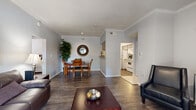 This well-appointed 2-bedroom, 2-bathroom single-floor residence at 11300 Expo Blvd in San Antonio, TX offers a thoughtfully designed layout with a cohesive, neutral color palette throughout. The living area features rich hardwood-style flooring and elegant crown molding, creating a polished ambiance that extends into the adjoining dining room. The dining space is framed by a pass-through window that connects directly to the kitchen, allowing for easy interaction and natural flow between rooms. The kitchen is finished with white cabinetry and tile flooring, offering a clean and functional workspace complemented by a dedicated pantry for added storage. Both bedrooms are generously proportioned, with the primary bedroom benefiting from multiple windows that invite natural light and views of the surrounding greenery. Each bedroom is served by its own walk-in closet with built-in shelving and hanging rods, providing ample storage. The bathrooms feature tub-shower combinations with tiled surrounds, wood-style flooring, and white vanity cabinetry. Additional highlights include multiple hallways for efficient circulation, a private patio for outdoor enjoyment, and three total closets throughout the unit, ensuring practical storage solutions across the entire residence.