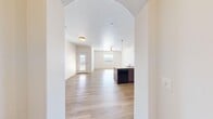 This single-story unit in Hurricane, Utah, offers a thoughtfully designed layout that efficiently utilizes its floor space. The open-concept kitchen and living area serves as the heart of the home, characterized by light wood-look flooring, a textured ceiling, and a distinctive arched entryway that adds architectural interest. The kitchen is well-equipped with dark wood cabinetry, granite-look countertops, a peninsula island with pendant lighting, and black appliances including a range, microwave, and refrigerator, alongside a dishwasher. Natural light filters through multiple windows, offering views of the surrounding Utah landscape and neighboring rooftops.

The bedroom features plush carpeting, a ceiling fan, and a large window framing scenic outdoor views. An additional room with wood-look flooring and generous window exposure provides flexible use as a dining or office space. The bathroom includes a tiled tub-and-shower combination, wood-look flooring, and a dark-vanity with granite-style countertops. A dedicated laundry area with washer and dryer hookups and built-in shelving adds everyday practicality to this clean, modern home.