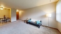 Located at 4301 Lincoln Swing in Ames, Iowa, this two-bedroom, one-bathroom unit offers a practical and comfortable single-floor layout. The open living room is generously sized, featuring plush carpeting, neutral walls, and a large window with vertical blinds that allows natural light to fill the space. The adjoining kitchen is efficiently designed with warm wood-tone cabinetry, tile flooring, a double sink, electric range, dishwasher, and track lighting overhead — providing all essential cooking amenities in a compact footprint. The primary bedroom is notably spacious, offering wall-to-wall carpet, a ceiling fan, and access to a dedicated closet with built-in shelving. The second bedroom is equally well-appointed, featuring carpet, a ceiling fan, a window with natural light, and a built-in wood shelving unit, making it a versatile space. A connecting hallway links the bedrooms to the full bathroom, which includes a single vanity with a wide countertop, medicine cabinet mirror, tile flooring, and a shower/tub combination. Warm wood-tone door frames and trim are consistent throughout, lending a cohesive, classic character to the entire unit.