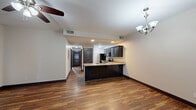 This two-bedroom, two-bathroom residence in Louisville, Kentucky offers a thoughtfully designed single-floor layout with a cohesive, modern aesthetic throughout. Rich hardwood-style flooring runs through the main living areas, complemented by dark espresso-toned cabinetry, doors, and trim that create a striking contrast against the neutral walls.

The open-concept kitchen is a standout feature, equipped with granite countertops, dark cabinetry, stainless steel appliances including a range and dishwasher, and a peninsula with a built-in sink that separates the kitchen from the combined dining and living area. A chandelier and recessed lighting illuminate this central space, while a ceiling fan enhances comfort in the living area. French doors with blinds allow natural light into one of the bedrooms, lending it an airy feel.

The primary bedroom is generously proportioned, with plush carpeting and direct access to a well-appointed en-suite bathroom featuring dual granite-topped vanities, dark cabinetry, tile flooring, and a glass-enclosed shower. The second bedroom also offers carpeted flooring and ample closet access. With five total closets throughout, storage is plentiful. A dedicated laundry area and a hallway connecting all rooms round out this well-organized and functional home.