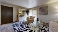 Located at 8406 E Harry St in Wichita, Kansas, this single-floor residence offers a well-organized layout designed for comfortable everyday living. The living room serves as the central gathering space, featuring a sliding glass door with vertical blinds that allows natural light to flow in and provides access to an outdoor area. Textured ceilings are consistent throughout the home, adding a classic architectural detail to each room. The dining area is positioned adjacent to the kitchen, connected via a pass-through window, and is equipped with a ceiling fan for added comfort. The kitchen features wood cabinetry, tile flooring, a range, and a full-size refrigerator, offering a practical and efficient cooking space. The primary bedroom is notably spacious, with wall-to-wall carpet and an expansive built-in closet system featuring rich, dark wood sliding doors that provide generous storage. A secondary bedroom with carpet flooring and ample natural light through a wide window offers flexibility for various uses. The full bathroom includes a tiled tub-shower combination, a single-sink vanity, and tile flooring, presenting a clean and functional design. Throughout the home, neutral wall tones and carpet flooring in the main living spaces contribute to a cohesive and understated aesthetic.