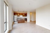 Located in Boston, MA 02210, this well-appointed 2-bedroom, 2-bathroom residence offers a thoughtfully designed open-concept layout. Light hardwood-style flooring flows throughout the main living areas, creating a bright and cohesive aesthetic. The combined living, dining, and kitchen area serves as the heart of the home, featuring rich walnut-toned cabinetry, granite countertops, a central island with pendant lighting, and stainless steel appliances including a refrigerator and dishwasher. Tall windows bathe the kitchen in natural light with views of the surrounding cityscape. A wide hallway connects the main living area to the private quarters, with three closets providing ample storage throughout. The spacious primary bedroom is highlighted by floor-to-ceiling windows on two walls, offering sweeping urban views and exceptional natural light, with light hardwood-style flooring. The second bedroom features plush carpeting, a large closet, and direct sightlines to the kitchen. Both bathrooms are finished with large-format tile flooring and warm wood vanities with granite countertops — one featuring a soaking tub and the other a walk-in shower. A dedicated laundry area and utility room round out this functional and stylish Boston residence.