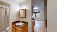 Located at 811 15th St in Greeley, Colorado, this studio efficiently utilizes its single-floor layout to offer a well-organized and functional living space. Light hardwood flooring runs throughout, lending warmth and visual continuity to every area.

The kitchen is a standout feature, equipped with warm oak cabinetry, dark countertops, a white electric range, built-in microwave, stainless steel refrigerator, and a double sink. A central island with a dark countertop provides additional prep space and serves as a natural transition into the dining area, where a built-in counter and open shelving unit offer extra storage and workspace versatility.

A dedicated built-in desk nook with upper cabinets and dual drawer pedestals provides a practical workspace. Adjacent to this area is a generously sized walk-in closet featuring double hanging rods and built-in shelving, offering ample storage.

Two bathrooms serve the space — one featuring a tub/shower combination with tiled surround, and another with an oak vanity, dark countertop, and a mirrored medicine cabinet. A large window with dark wood trim fills the main living area with natural light and views of the surrounding greenery, enhancing the overall brightness and openness of this compact yet cleverly designed space.
