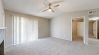This single-story, 2-bedroom, 2-bathroom home offers a thoughtfully organized layout with a neutral color palette and a warm, understated ambiance throughout. The living room serves as a central gathering space, highlighted by a painted brick fireplace with a classic mantel and vaulted ceilings that add an open, airy feel. A ceiling fan with integrated lighting enhances comfort, while vertical blinds on a sliding glass door allow for natural light control. Soft wall-to-wall carpet extends throughout the living and bedroom areas, contributing to a cozy atmosphere.

The galley-style kitchen features gray cabinetry on both sides, white countertops, light vinyl plank flooring, and black appliances including a refrigerator, range, and overhead microwave. A pass-through counter connects the kitchen to the main living area.

The spacious primary bedroom includes a ceiling fan, vaulted ceiling, and a sliding glass door with vertical blinds, along with access to a walk-in closet equipped with built-in shelving and hanging rods. The second bedroom offers carpet flooring, a ceiling fan, and a bright window. Both bathrooms feature light vinyl plank flooring, with one including a soaking tub and shower combination and the other a wide vanity with ample cabinet storage.