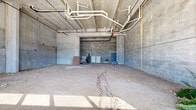 Located at 850 S Gaines St in Tallahassee, FL, this single-floor commercial shell space presents a substantial open footprint ideal for a ground-up buildout. The interior is currently in raw condition, featuring exposed concrete masonry unit (CMU) block walls, bare concrete columns, and an unfinished dirt and gravel subfloor throughout. The overhead structure reveals exposed concrete ceiling beams and a network of rough-in MEP (mechanical, electrical, and plumbing) conduit and pipe runs, indicating that foundational infrastructure is already in place for future build-out.

The space benefits from a series of large, multi-pane windows along one exterior wall, allowing substantial natural light to filter into the open interior and offering views of the surrounding landscape. Ceiling heights are notably generous, contributing to an expansive, loft-like atmosphere well-suited for a variety of commercial uses. A steel utility door provides secondary access, and structural columns punctuate the floor plate without significantly interrupting the open plan.

The current state of the space offers a blank canvas, providing a future tenant or owner with maximum flexibility to design and configure the layout to suit retail, creative, office, or mixed-use purposes. The raw, industrial character of the existing structure may also serve as an aesthetic foundation for a variety of contemporary build-out styles.