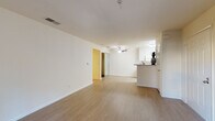This single-floor residence offers a clean, modern aesthetic throughout its thoughtfully designed layout. The open-concept living and dining area is finished with light wood-style flooring, crisp white walls, and a ceiling fan, creating a bright and airy atmosphere. A sliding glass door leads to an outdoor balcony, inviting natural light into the space and providing views of the surrounding neighborhood. A cozy fireplace serves as a focal point in the living area, adding warmth and character.

The galley-style kitchen is efficiently laid out, featuring white cabinetry, a full suite of white appliances including a stove, microwave, and refrigerator, and granite-patterned countertops. A peninsula counter with a sink opens toward the living area, enhancing the sense of connectivity between spaces.

The bedroom is carpeted for comfort and includes a walk-in closet with mirrored sliding doors, offering generous storage. A window frames outdoor greenery, filling the room with natural light. The bathroom is clean and well-appointed, with a granite-top vanity, an integrated sink, a large mirror, and a shower enclosure, all finished with light wood-style flooring for a cohesive look throughout.