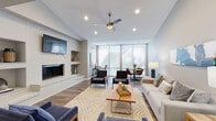 Located at 1710 Somerset Pl in Hurstbourne Acres, Kentucky, this single-floor property showcases a thoughtfully designed open-concept layout that seamlessly blends living, dining, and workspace areas. The main living area is anchored by a striking white brick fireplace wall with built-in shelving and a wall-mounted television, complemented by soaring vaulted ceilings that amplify the sense of space and airiness throughout. Rich hardwood flooring runs continuously across the entire space, adding warmth and visual cohesion.

A ceiling fan with integrated lighting enhances both comfort and style in the main living zone, which is furnished with a generous seating arrangement centered around a live-edge wood coffee table. The dining area is positioned near an expansive bank of floor-to-ceiling windows fitted with sheer roller shades, flooding the space with abundant natural light while offering views to the outdoors. Adjacent to the dining area, a dedicated workspace features the same generous natural light, built-in shelving, and equestrian-themed artwork that adds a distinctive character throughout the home. The neutral gray walls and clean architectural lines lend the space a modern, sophisticated ambiance well-suited for both everyday living and entertaining.
