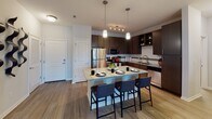 This well-appointed 2-bedroom, 2-bathroom residence in Melbourne, Florida offers a thoughtfully designed single-floor layout that balances comfort and modern style. The open-concept living area features wood-style flooring, a ceiling fan, and an abundance of natural light streaming through large windows and a glass-panel door that opens to a private balcony with outdoor views. The kitchen is a standout space, equipped with stainless steel appliances, rich dark cabinetry, a subway tile backsplash, granite countertops, and a center island with pendant lighting and bar seating — ideal for both everyday meals and entertaining. Both bedrooms are generously sized and carpeted, each featuring ceiling fans, large windows with natural light, and ample room for furnishings. The primary bedroom includes a full en-suite bathroom with a tiled tub-shower combination, granite vanity, and wood-style flooring. The second bathroom mirrors the same refined finishes, including a granite countertop vanity and light flooring. Throughout the residence, neutral tones and clean architectural lines create a cohesive, contemporary ambiance. Track lighting and pendant fixtures add functional elegance to the kitchen, while the overall layout promotes a seamless flow between living, dining, and private spaces.