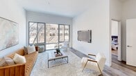 This thoughtfully designed unit at The Althea, located at 100 Evergreen Pl in East Orange, NJ, offers a bright and modern living environment across a single floor. The open-concept living and dining area is a standout feature, anchored by large floor-to-ceiling sliding glass doors that flood the space with natural light and provide outdoor views of surrounding greenery. Smooth hardwood-style flooring and crisp white walls create a clean, contemporary aesthetic throughout.

The kitchen is efficiently laid out with dark shaker-style cabinetry, granite countertops, and a full suite of stainless steel appliances, including a gas range, built-in microwave, and dishwasher. Light tile flooring adds a polished contrast to the rich cabinetry tones.

The bedroom is a serene retreat, featuring hardwood-style flooring, neutral walls, and a window that invites natural light. Its generous proportions comfortably accommodate a full bedroom suite.

The bathroom is finished with striking marble-look tile flooring, a clean white vanity with ample storage, and a bright mirror, all contributing to a spa-like ambiance. The overall design of this unit balances modern functionality with inviting warmth.