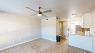 Located at 1500 East Broadway Road in Tempe, Arizona, this efficiently laid-out single-floor unit offers a well-considered use of space across a living room, kitchen, bathroom, hallway, and closet. The living area features light wood-look flooring, neutral walls, and a ceiling fan with integrated lighting, creating a bright and airy atmosphere. A window with horizontal blinds allows natural light to filter in while providing outdoor views. The kitchen is a standout feature, showcasing granite countertops, crisp white shaker-style cabinetry, a slate-blue subway tile backsplash, and stainless steel appliances including a full-size refrigerator. An in-unit washer is conveniently integrated beneath the counter, adding practical functionality. The bathroom continues the cohesive design aesthetic with a granite-topped vanity, white cabinetry, a framed mirror, and a full tub-shower combination. Wood-look flooring extends throughout, tying the space together in a clean, modern style. The overall design emphasizes smart, functional living with contemporary finishes, making this unit a well-appointed option in the heart of Tempe.