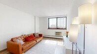 Located at 115 Second Ave S in downtown Minneapolis, this one-bedroom, one-bathroom unit offers a efficiently designed layout across a single floor. A welcoming hallway with a large built-in closet leads into the main living areas.

The living room is a bright, open space featuring light wood-style flooring, crisp white walls, and a large window fitted with vertical blinds that frames views of the Minneapolis skyline. A baseboard heating system and wall-mounted AC unit provide year-round climate control.

The galley-style kitchen is clean and functional, outfitted with white cabinetry on both sides, laminate countertops, a full-size refrigerator, gas range, and a single-basin sink. An open pantry area at the far end provides additional storage.

The bedroom offers a comfortable, carpeted retreat with its own window overlooking the city, providing natural light throughout the day. The room accommodates a full-size bed and dresser with ease.

The full bathroom is finished in white tile and includes a single-vanity with a lighted mirror, a shower/tub combination, and tile flooring. The overall aesthetic throughout the unit is clean and neutral, making it a practical and move-in ready urban residence.