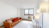 Located at 115 Second Ave S in downtown Minneapolis, this one-bedroom, one-bathroom unit offers a efficiently designed layout across a single floor. A welcoming hallway with a large built-in closet leads into the main living areas.

The living room is a bright, open space featuring light wood-style flooring, crisp white walls, and a large window fitted with vertical blinds that frames views of the Minneapolis skyline. A baseboard heating system and wall-mounted AC unit provide year-round climate control.

The galley-style kitchen is clean and functional, outfitted with white cabinetry on both sides, laminate countertops, a full-size refrigerator, gas range, and a single-basin sink. An open pantry area at the far end provides additional storage.

The bedroom offers a comfortable, carpeted retreat with its own window overlooking the city, providing natural light throughout the day. The room accommodates a full-size bed and dresser with ease.

The full bathroom is finished in white tile and includes a single-vanity with a lighted mirror, a shower/tub combination, and tile flooring. The overall aesthetic throughout the unit is clean and neutral, making it a practical and move-in ready urban residence.
