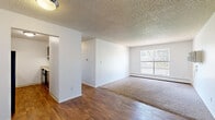 Located at 1209 26th Ave in Greeley, Colorado, this two-bedroom, one-bathroom residence offers a practical and efficient single-floor layout. The living room serves as the central gathering space, featuring warm hardwood-style flooring that transitions to plush carpet, a large window that invites natural light and outdoor views of surrounding greenery, a textured ceiling, and a baseboard heating unit. A wall-mounted air conditioning unit provides additional climate control comfort.

The kitchen is equipped with dark wood cabinetry, ample counter space, a double-basin stainless steel sink, a dishwasher, and a range, all set atop easy-to-maintain hardwood-style flooring — providing a functional space for everyday cooking.

Both bedrooms are carpeted and finished with neutral tones and textured ceilings. Each room includes a closet with a hanging rod for storage. The primary bedroom offers a comfortable footprint with room for standard furnishings. The second bedroom is similarly appointed with its own closet access.

The bathroom features a full tub-shower combination with clean white tile surround and chrome fixtures. A hallway connects the rooms, contributing to the unit's straightforward and accessible flow throughout.