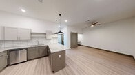 Located at 627 E Emma Ave in Springdale, Arkansas, this thoughtfully designed 2-bedroom, 2-bathroom residence offers a clean, contemporary aesthetic throughout its single-floor layout. The open-concept kitchen and living area serves as the heart of the home, featuring light wood-look flooring, a ceiling fan, and a stylish barn door accent. The kitchen is well-appointed with two-tone cabinetry in gray and white, granite countertops, a subway tile backsplash, a center island with pendant lighting, stainless steel appliances including a refrigerator, dishwasher, and range, as well as a double undermount sink. Both bedrooms are comfortably sized, each with ceiling fans and light flooring. The primary bedroom includes a sliding glass door that opens to a private balcony with outdoor views. The two bathrooms mirror the home's modern design, featuring granite-topped vanities with undermount sinks, framed mirrors, and tile-style flooring. One bathroom includes a full tub and shower combo. Additional conveniences include a dedicated laundry area, a utility room, closets, and a hallway connecting all spaces. The unit presents a bright, move-in-ready environment with consistent finishes throughout.
