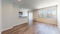 This three-story home offers a thoughtfully designed layout spread across multiple levels, connected by a staircase with classic metal balusters. The main living area is open and airy, featuring warm hardwood-style flooring, recessed lighting, and large windows with vertical blinds that invite natural light throughout the space. The kitchen flows seamlessly into the living area via a peninsula with granite countertop surfaces, providing both workspace and a casual dining option. Rich dark-toned cabinetry pairs with stainless steel appliances, including a refrigerator, range, and over-the-range microwave, completing a functional and stylish culinary space.

A half bathroom on one level features a dark wood vanity with a granite countertop, a single-basin sink, and a large mirror. The full bathrooms are finished with large-format gray stone-look tile extending from floor to ceiling. One bathroom includes a soaking tub with tiled surround, while another offers a walk-in shower with a mosaic tile floor and open entry. Upper-level bedrooms are carpeted for comfort, with windows providing natural light. The overall aesthetic is clean, modern, and neutral throughout.