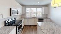 Located at 3717 Margaret Mitchell Ct in Charlotte, NC, this multi-story home spans three floors and offers a thoughtfully designed layout with contemporary finishes throughout. The kitchen is a standout feature, showcasing granite countertops, white cabinetry with brushed nickel hardware, stainless steel appliances including a refrigerator, range, and microwave, and a large island with pendant lighting — all tied together by hardwood-style flooring and a window that fills the space with natural light. The open living area continues the hardwood-style flooring, complemented by recessed lighting, ceiling fans, and multiple windows that invite an abundance of daylight. Bedrooms are finished with plush carpeting, ceiling fans, and generous closet space, including walk-in shelving systems. The bathrooms are well-appointed with granite vanity tops, white cabinetry, and a tiled soaking tub, maintaining the clean and modern aesthetic found throughout the home. A half bath provides added convenience. The home's three-floor layout, visible in the architectural overview, features a central staircase connecting each level, offering a sense of spaciousness and vertical flow. Neutral tones and clean lines define the overall ambiance, creating a bright and move-in ready environment.