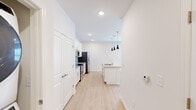 Located at 1994 US-72 E in Huntsville, Alabama, this single-floor unit offers a clean, contemporary design with a bright, neutral color palette throughout. The open-concept kitchen is a standout feature, showcasing white cabinetry, granite countertops, a central island with an undermount sink, stainless steel appliances, and stylish black pendant lighting overhead. Light wood-style flooring runs through the main living and kitchen areas, lending warmth and continuity to the space. The living area is generously sized, featuring a ceiling fan with light fixture and a window fitted with blinds that allows natural light to fill the room. The bedrooms are carpeted for comfort, each equipped with a ceiling fan and windows with blinds. One bedroom includes direct access to a spacious walk-in closet with wire shelving and carpeted flooring, offering ample storage. The bathroom features large-format tile surrounding a full soaking tub and shower combination, complemented by brushed nickel fixtures and wood-style flooring. Recessed lighting throughout the main areas ensures consistent, well-distributed illumination. The overall ambiance of the space is fresh and move-in ready, with a cohesive modern aesthetic that balances function and style.