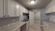 This two-floor townhome offers a well-designed layout with consistent, contemporary finishes across every room. Light luxury vinyl plank flooring flows throughout the space, complemented by crisp white trim and a soft gray color palette that lends a clean and modern feel to the interior.

The kitchen area is a standout feature, showcasing an abundance of white raised-panel cabinetry both above and below the counters, providing generous storage. The granite countertops add a touch of elegance, while a stainless steel sink and updated fixtures complete the functional workspace.

The living areas are open and welcoming, with natural light filtering in through windows fitted with blinds. The rooms are well-proportioned and versatile, suited for a variety of uses. Several bedrooms feature angled ceilings and closet access, adding architectural character to the upper level.

The bathrooms are neatly appointed; one features a full tub-and-shower combination with built-in shelving, while another offers a wall-mounted sink and a window that brings in natural light. A dedicated laundry room includes dual rows of cabinetry with granite countertops on both sides, along with a utility sink — a highly practical and well-equipped space. Throughout, the townhome maintains a tidy, move-in-ready condition with thoughtful attention to detail.