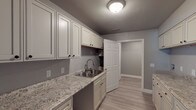 This two-floor townhome offers a well-designed layout with consistent, contemporary finishes across every room. Light luxury vinyl plank flooring flows throughout the space, complemented by crisp white trim and a soft gray color palette that lends a clean and modern feel to the interior.

The kitchen area is a standout feature, showcasing an abundance of white raised-panel cabinetry both above and below the counters, providing generous storage. The granite countertops add a touch of elegance, while a stainless steel sink and updated fixtures complete the functional workspace.

The living areas are open and welcoming, with natural light filtering in through windows fitted with blinds. The rooms are well-proportioned and versatile, suited for a variety of uses. Several bedrooms feature angled ceilings and closet access, adding architectural character to the upper level.

The bathrooms are neatly appointed; one features a full tub-and-shower combination with built-in shelving, while another offers a wall-mounted sink and a window that brings in natural light. A dedicated laundry room includes dual rows of cabinetry with granite countertops on both sides, along with a utility sink — a highly practical and well-equipped space. Throughout, the townhome maintains a tidy, move-in-ready condition with thoughtful attention to detail.