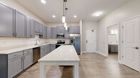 Located at 1384 Empire Blvd in Rochester, NY, this single-floor, two-bedroom, two-bathroom residence offers a thoughtfully designed layout with contemporary finishes throughout. The open-concept kitchen serves as a central highlight, featuring gray shaker-style cabinetry extending to the ceiling, white quartz countertops, a full suite of stainless steel appliances including a refrigerator with ice maker, range, microwave, and dishwasher, and a freestanding island with pendant lighting overhead. Wood-look plank flooring flows throughout the main living areas, adding warmth and cohesion to the space.

The living room is generously sized with access to a sliding glass door that introduces natural light, while neutral-toned walls provide a versatile backdrop. Both bedrooms are carpeted and feature ample proportions; the primary bedroom is notably spacious and connects to a private en-suite bathroom with a dual-sink vanity, gray cabinetry, and a soaking tub. The secondary bathroom mirrors the same refined aesthetic with a single-sink vanity and tub-shower combination. Two closets provide dedicated storage, completing this well-appointed residence.
