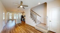 Located in Lenexa, Kansas, this two-story, 4-bedroom, 2-bathroom home offers a well-designed layout spread across two floors. The main level features an open-concept kitchen and living area bathed in natural light from large windows. The kitchen is a standout, showcasing a large center island with a striking marble-look countertop, undermount sink, and pendant lighting. Gray shaker-style cabinetry, stainless steel appliances, a built-in wine rack, and wood-look flooring complete the space. An adjacent dining area features vaulted ceilings and a statement chandelier, further enhanced by oversized windows overlooking the outdoors. The spacious primary bedroom includes a tray ceiling with a ceiling fan, plush carpeting, and a generous walk-in closet with built-in shelving and double hanging rods. The primary bathroom impresses with marble-look tile flooring, dark wood double vanity, a glass-enclosed shower, and elegant lighting. Additional bedrooms offer comfortable proportions with carpet and ample closet space. The upper level provides a more intimate setting for the remaining bedrooms. An attached garage with an automatic opener rounds out this well-appointed home.
