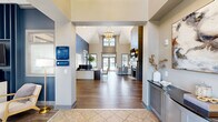 Located at 226 Barrington Place in Aurora, Ohio, this single-story community clubhouse offers a well-appointed amenity hub designed to serve residents with both style and function. The centerpiece of the interior is a soaring great room with dramatic vaulted ceilings, a tiered chandelier, and warm hardwood-style flooring. A sleek fireplace with shiplap surround anchors one wall, while floor-to-ceiling windows and glass doors flood the space with natural light and frame views of the outdoor pool area. The leasing office features a dedicated workspace with a bold navy accent wall, custom artwork, and direct sightlines to the main entrance. A comfortable lounge area near the entry welcomes visitors with plush seating and tasteful décor. The business center provides a quiet, focused workspace equipped with multiple computer workstations, a printer, and ample desk space. The fitness center is well-equipped with cable machines, cardio equipment including stair climbers and ellipticals, free weights, and wall-mounted TVs. Outside, a expansive resort-style swimming pool is surrounded by a generous sun deck lined with lounge chairs, a covered gazebo, and lush landscaping — offering a vibrant outdoor retreat for residents throughout the warmer months.