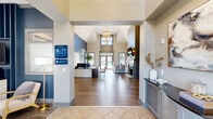 Located at 226 Barrington Place in Aurora, Ohio, this single-story community clubhouse offers a well-appointed amenity hub designed to serve residents with both style and function. The centerpiece of the interior is a soaring great room with dramatic vaulted ceilings, a tiered chandelier, and warm hardwood-style flooring. A sleek fireplace with shiplap surround anchors one wall, while floor-to-ceiling windows and glass doors flood the space with natural light and frame views of the outdoor pool area. The leasing office features a dedicated workspace with a bold navy accent wall, custom artwork, and direct sightlines to the main entrance. A comfortable lounge area near the entry welcomes visitors with plush seating and tasteful décor. The business center provides a quiet, focused workspace equipped with multiple computer workstations, a printer, and ample desk space. The fitness center is well-equipped with cable machines, cardio equipment including stair climbers and ellipticals, free weights, and wall-mounted TVs. Outside, a expansive resort-style swimming pool is surrounded by a generous sun deck lined with lounge chairs, a covered gazebo, and lush landscaping — offering a vibrant outdoor retreat for residents throughout the warmer months.