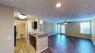 This single-floor residence offers a thoughtfully designed open-concept layout that seamlessly connects the kitchen, dining, and living areas. The kitchen is equipped with dark espresso cabinetry, granite countertops, black appliances including a range, microwave, and refrigerator, and a peninsula with a sink that opens directly to the living space. Crown molding accents the living and dining areas, which feature rich, dark hardwood-style flooring and a ceiling fan. French doors provide access to an outdoor area, flooding the living space with natural light alongside additional side windows.

The bedrooms are carpeted for comfort, with warm neutral tones carried throughout. The primary bedroom connects to a dedicated bathroom and a walk-in closet, offering practical convenience. A secondary bedroom features carpet flooring and a window with blinds admitting soft natural light. The bathrooms are finished with granite-topped dark vanities, wood-style flooring, and full tub-and-shower combinations with tile surrounds. Additional storage is available via a walk-in closet visible from the main hallway. Overall, the residence presents a clean, functional, and cohesive aesthetic with consistent finishes across every room.