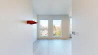 Located at 5633 N Montana Ave in Portland, Oregon, this efficiently designed one-bedroom, one-bathroom unit offers a clean, modern aesthetic across its single floor. Light hardwood flooring flows consistently throughout the main living areas, contributing to a bright and cohesive feel.

The open kitchen-living room combination serves as the heart of the unit. The kitchen stands out with its bold design, featuring dark matte cabinetry, glossy dark countertops, a matching tile backsplash, a black undermount sink, and stainless steel appliances including a Whirlpool range and built-in microwave. The adjacent living area benefits from an abundance of natural light, delivered through tall, vertically oriented windows that frame views of the surrounding Portland neighborhood and tree canopy.

The bedroom is a well-proportioned, serene space with crisp white walls and large windows that allow ample daylight and offer pleasant outdoor views. Light hardwood flooring continues here, maintaining the unit's consistent and airy style.

The bathroom is cleanly finished in white, with a full tub-shower combination, matte black hardware and fixtures, and durable tile flooring in a neutral tone. A dedicated entrance area and additional storage complete the thoughtful layout of this compact yet functional unit.