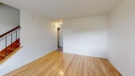 Located at 466 Ash St in Willimantic, CT, this 2-bedroom, 2-bathroom residence is thoughtfully arranged across three floors. The ground level provides access to a garage with a clean, epoxy-coated concrete floor and exposed utility infrastructure. The main living floor hosts a bright living room, a well-equipped kitchen, and hallway connections between rooms. The kitchen features warm honey-toned wood cabinetry, granite-style countertops, and white appliances including a range, dishwasher, and refrigerator, all set atop light hardwood-style flooring. The upper floor contains both bedrooms, including a generously sized primary bedroom, and two full bathrooms. Throughout the living areas, polished light hardwood floors lend a warm, consistent aesthetic, complemented by crisp white walls and natural light streaming through windows that offer views of surrounding greenery. The bathrooms are finished with white vanities, mirrors, and combination tub-shower units. A hardwood staircase connects the floors, adding a classic touch to the home's clean, neutral design. Baseboard heating is present throughout, ensuring year-round comfort in this practical and well-maintained Willimantic residence.