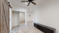 This single-floor unit offers a thoughtfully designed interior that balances contemporary updates with distinctive architectural character. Light wood-style flooring runs throughout the space, creating a warm and cohesive feel across every room.

The main living area is bright and open, featuring a ceiling fan with recessed lighting and clean white walls that enhance the sense of space. A sliding mirrored closet provides generous storage, while the layout flows naturally toward the entry.

The kitchen is a standout area, showcasing an exposed red brick accent wall that adds warmth and texture to the otherwise modern design. White shaker-style cabinetry with dark countertops lines one wall, complemented by black appliances and a pendant light overhead. A rustic sliding barn door connects the kitchen area to the living space, adding a charming farmhouse-inspired touch. A window above the sink brings in natural light and an outdoor view of the surrounding neighborhood.

A separate room with its own exposed brick wall and large double-hung windows offers additional natural light and street views, with a wall-mounted heating unit included for comfort.

The bathroom is clean and bright, finished in white tile with wood-style flooring. It includes a full soaking tub with an overhead shower, a white vanity with chrome fixtures, and a window with blinds for natural ventilation and light.