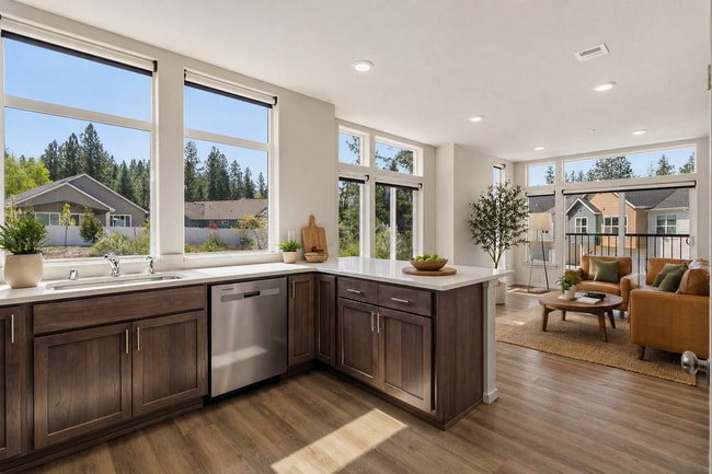 Cocina y sala de estar luminosas y de concepto abierto con acabados modernos, grandes ventanales y vistas al vecindario, que ofrecen una combinación perfecta de estilo y comodidad. - Lofts at Garden District
