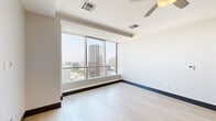 Located in the heart of Dallas at 1400 Pacific Ave, this sophisticated 2-bedroom, 4-bathroom residence offers a refined urban living experience across a single thoughtfully designed floor. The open-concept kitchen is outfitted with rich wood cabinetry extending to the ceiling, white quartz countertops, and a full suite of stainless steel appliances, including a French door refrigerator, electric range with microwave, and dishwasher — all complemented by light hardwood flooring. The generously sized primary bedroom features plush carpeting, a ceiling fan, and access to a spacious walk-in closet with built-in shelving and hanging rods. The en-suite primary bathroom is elegantly finished with large-format tile flooring, a glass-enclosed walk-in shower, a soaking tub, and wood-toned vanity cabinetry. The second bedroom mirrors the comfort of the primary, with soft carpet and its own ceiling fan. Both bedrooms benefit from expansive floor-to-ceiling windows that frame stunning panoramic views of the Dallas skyline. Two walk-in closets provide ample storage throughout. A dedicated laundry room with in-unit washer and tile flooring adds everyday convenience. The bathrooms throughout feature clean, modern finishes with built-in cabinetry for additional storage.