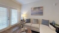 This single-floor residence offers a cohesive, modern design highlighted by a consistent palette of soft neutrals, white cabinetry, and warm wood-style flooring throughout the main living areas. The kitchen serves as a central focal point, featuring white shaker-style cabinetry, granite countertops, a dark subway tile backsplash, and a full suite of stainless steel appliances including a range, microwave, and refrigerator. A kitchen island with seating provides additional prep space and a casual dining option, while recessed lighting illuminates the area effectively.

The open layout connects the kitchen seamlessly to the living area, which features crown molding, natural light from large windows with blinds, and durable wood-style flooring. The primary bedroom offers plush carpeting, a ceiling fan, and a window that brings in natural light. A second bedroom, also carpeted and fan-equipped, comfortably accommodates twin beds. Two bathrooms serve the residence: one features a granite vanity, white cabinetry, and a shower-tub combination, while the second offers a granite-topped vanity, natural light from a window, and clean, neutral finishes throughout.