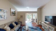 This single-floor residence offers a thoughtfully organized layout that balances comfort and functionality across its living spaces. The living room serves as a welcoming centerpiece, featuring warm hardwood-style flooring, neutral-toned walls, and an open sightline into the dining area beyond. A large sliding glass door in the dining space floods the area with natural light and provides views of the surrounding greenery, creating a bright and airy atmosphere ideal for everyday living or entertaining.

The kitchen is well-equipped with stainless steel appliances, including a refrigerator, range, microwave, and dishwasher. Warm wood cabinetry pairs with granite-look countertops and a double undermount sink, offering ample workspace and storage. A peninsula layout connects the kitchen to adjacent areas, promoting an open flow throughout.

The primary bathroom features a granite-topped vanity with wood cabinetry, hardwood-style flooring, and a tub-shower combination. A second bathroom provides a walk-in shower, matching vanity, and built-in shelving for added storage convenience. In-unit laundry is also present.

The bedroom is a calm, carpeted retreat with generous space and easy access to the primary bath. Throughout the residence, consistent finishes and a neutral palette contribute to a cohesive and inviting ambiance.